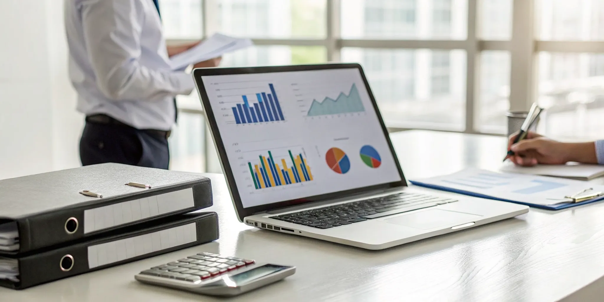 Laptop with financial charts and documents used for business tax compliance services.